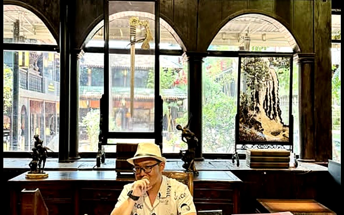 Đặng Tấn Thiện ngồi bên bàn gỗ trong căn phòng cửa vòm.